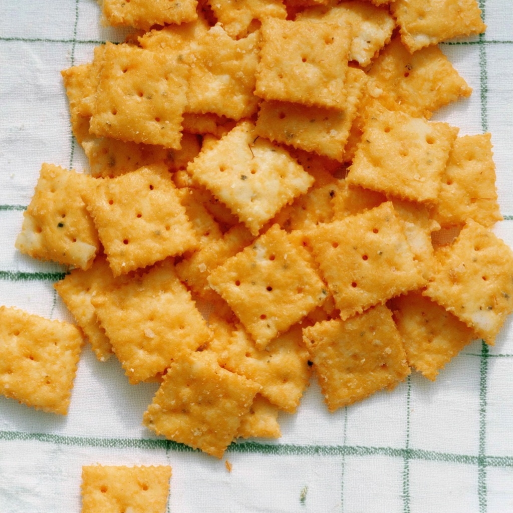 House-made herb cheese crackers scattered on a green-checked linen cloth