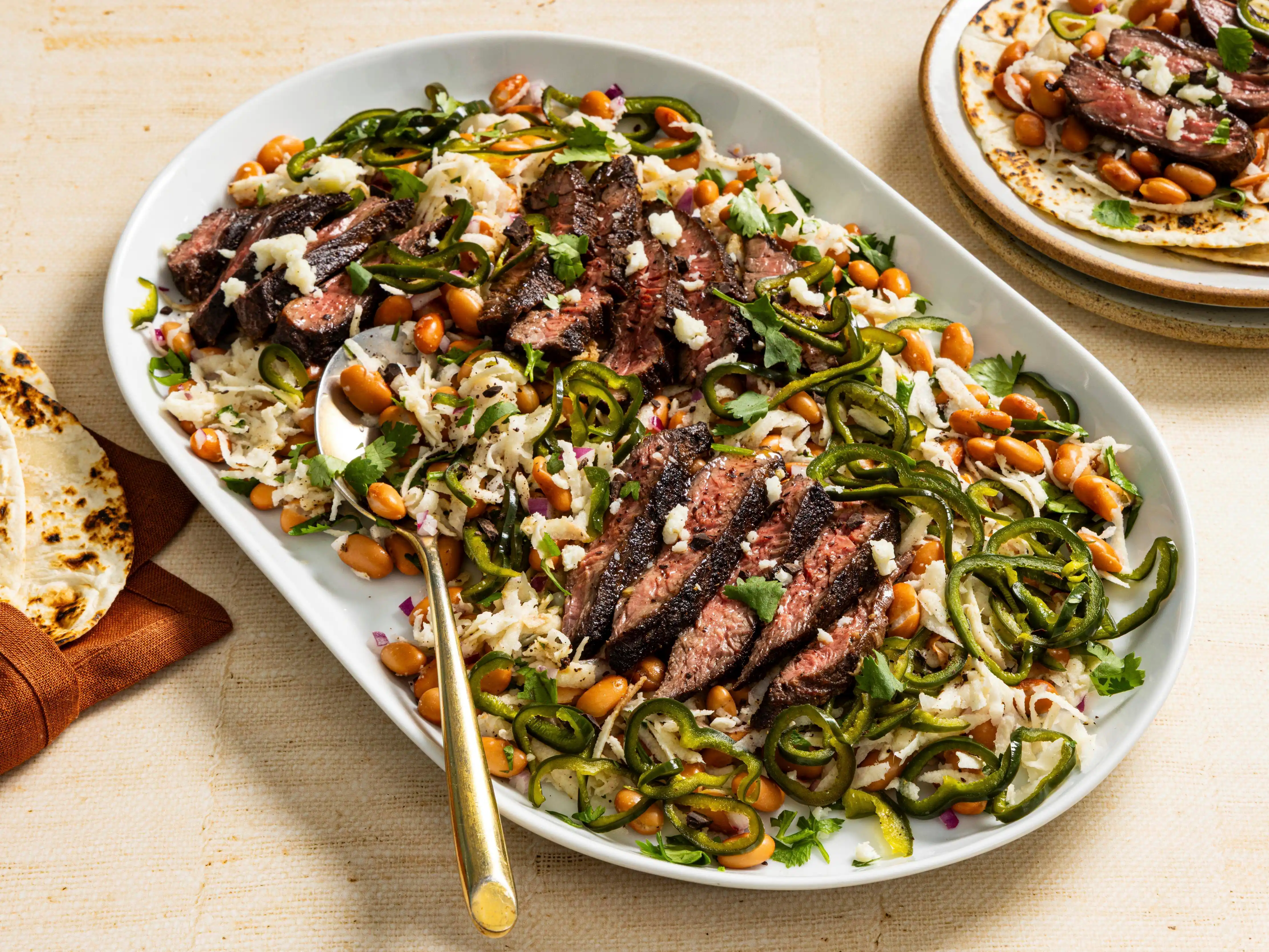 Sliced skirt steak over slaw with pinto beans, jalapeño, cilantro, and cotija